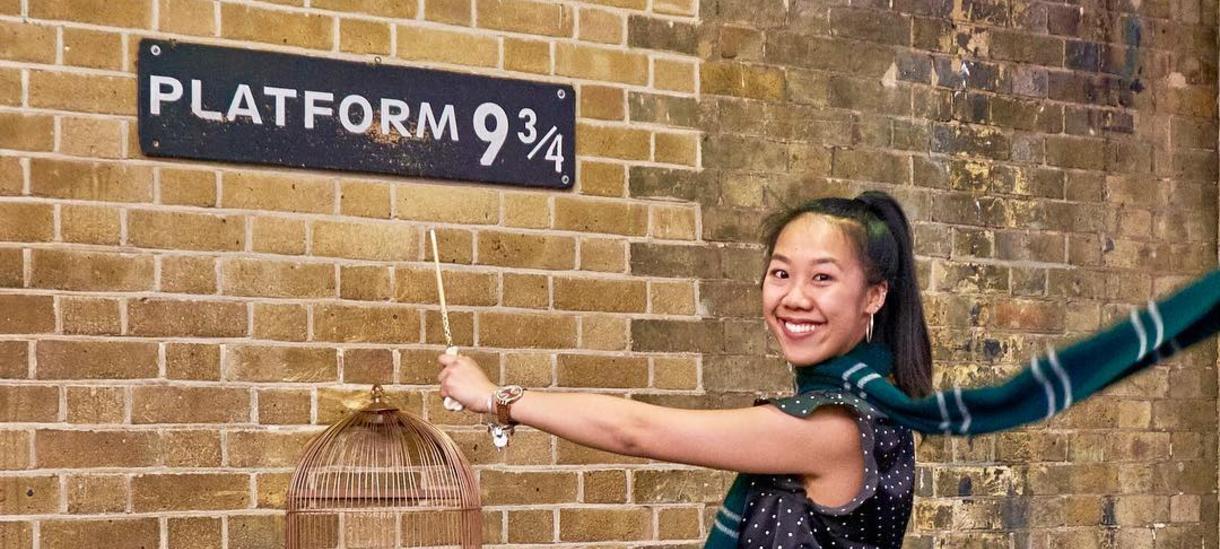 一名学生在伦敦国王十字车站的“9又3/4站台”标志前微笑着摆拍。