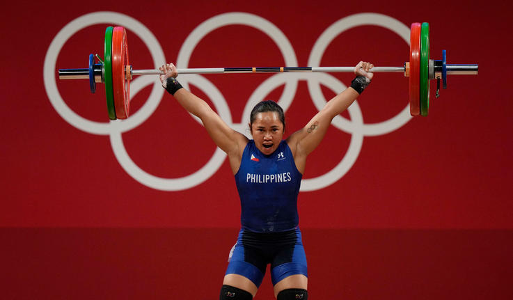 Hidilyn Diaz lifting weights above her head and looking strong