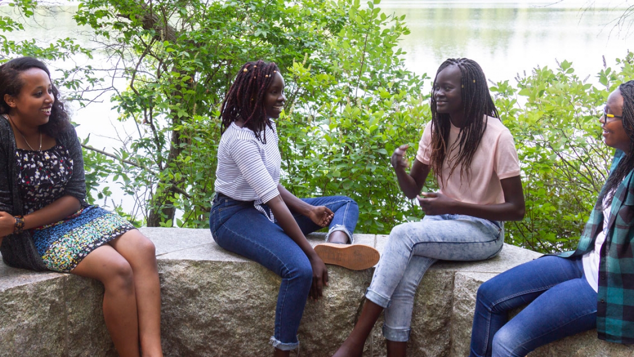 四个学生坐在瓦班湖边聊天。