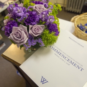 A photo of a bouquet of purple roses beside the commencement program.