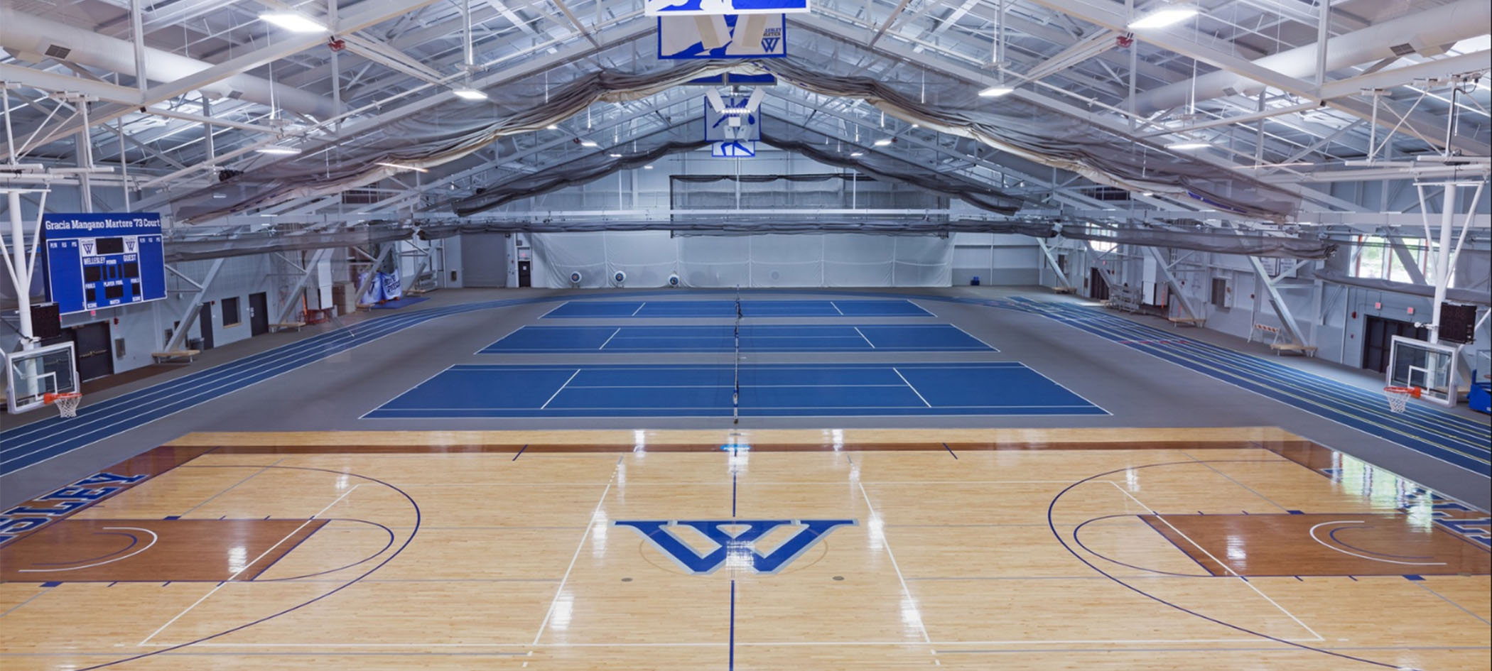 宽阔的KSC竞技场显示了三个蓝色的网球场和一个篮球场，中间有蓝色的韦尔斯利W。