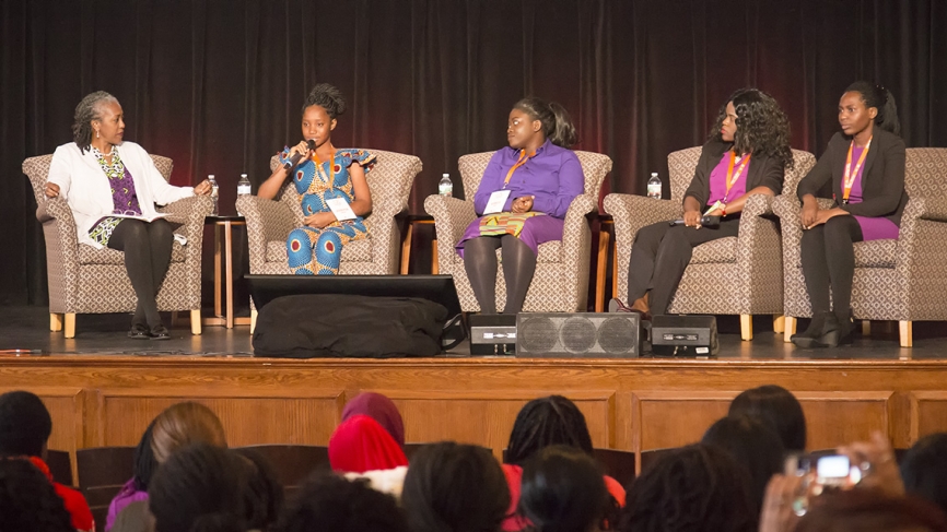 四个女学生坐在一个舞台主持人,回答问题。