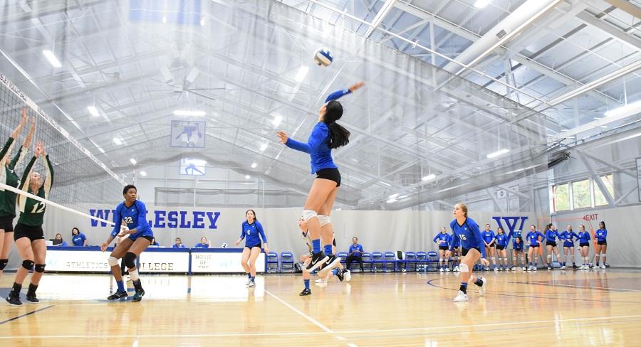 Wellesley College volleyball team player hits a volleyball across the net to the opposing team